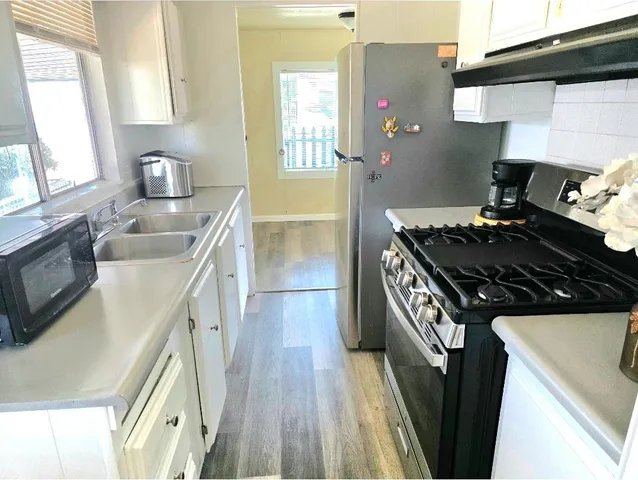 a kitchen with a stove a sink and wooden floor