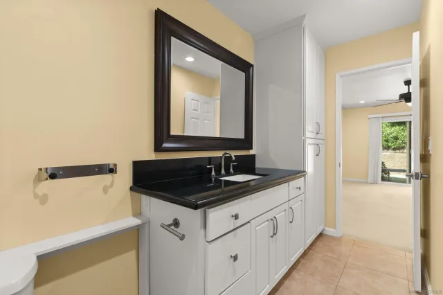 a bathroom with a granite countertop sink and a mirror