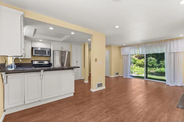 a open kitchen with white cabinets and wooden floor