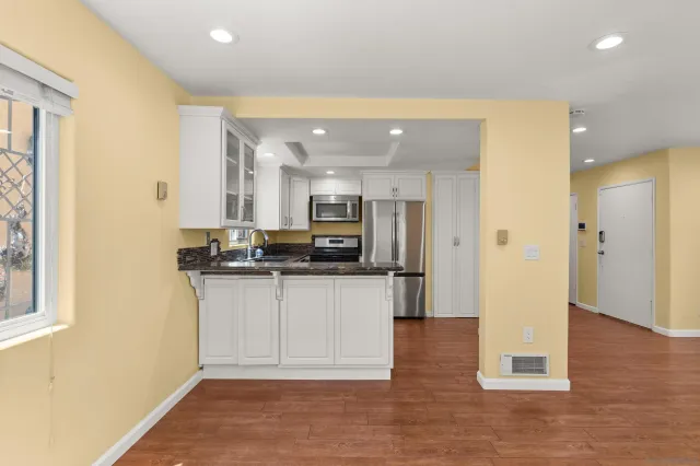a view of kitchen with stainless steel appliances granite countertop a refrigerator and a stove top oven