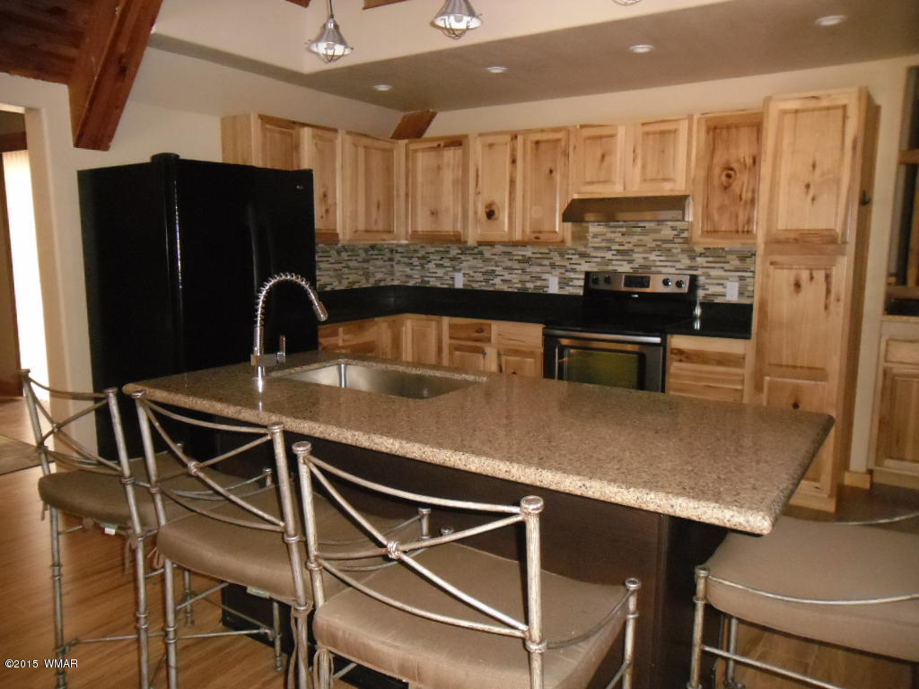 3463 Quail Run Road Overgaard, AZ 85933 - Photo 16 of 37 a kitchen with kitchen island granite countertop a table chairs sink and refrigerator