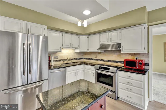 a kitchen with kitchen island granite countertop a stove cabinets and refrigerator