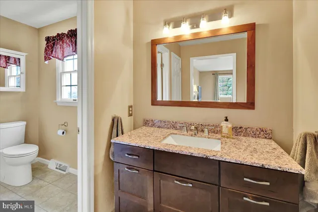 a bathroom with a granite countertop toilet sink and mirror