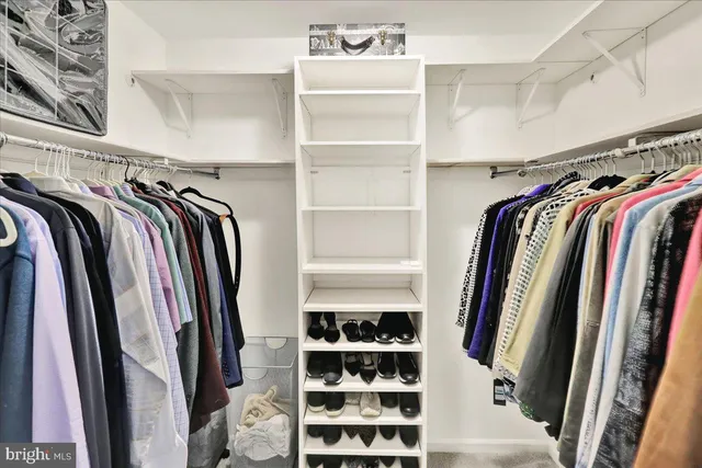 a view of walk in closet with clothes and shoes with white walls