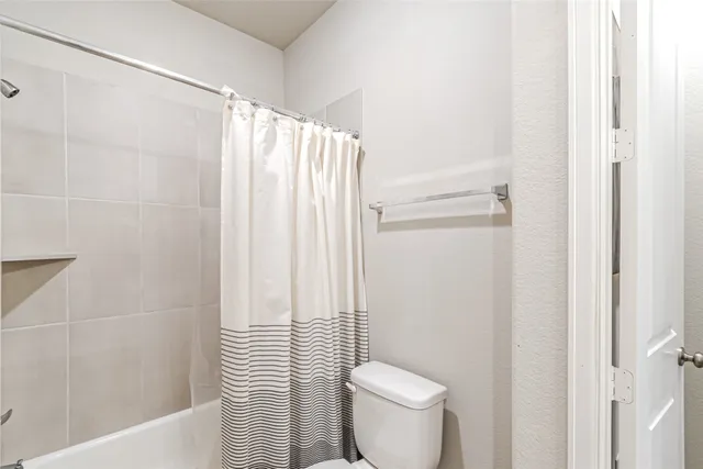 a white toilet sitting next to a shower curtain