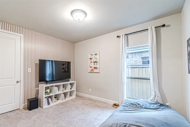 a living room with a flat screen tv on dresser and a window