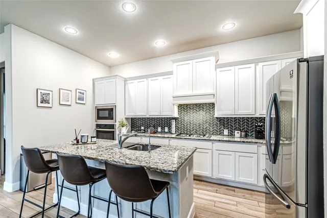 a kitchen with stainless steel appliances granite countertop a stove refrigerator sink and cabinets