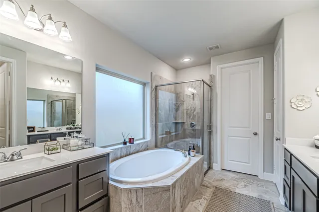 a bathroom with a tub sink double vanity and mirror