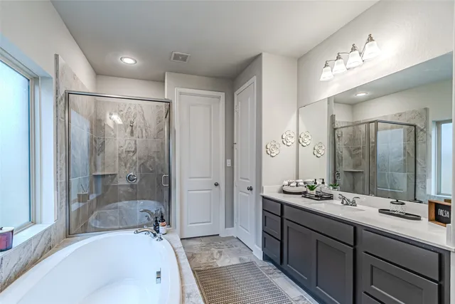 a en suite bathroom with double vanity sinks a mirror and a bathtub