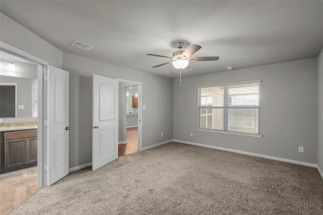 an empty room with chandelier fan and windows