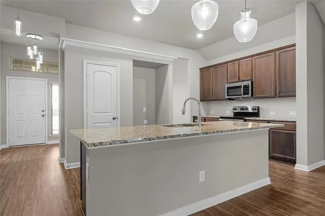 a kitchen with granite countertop a sink cabinets and wooden floor