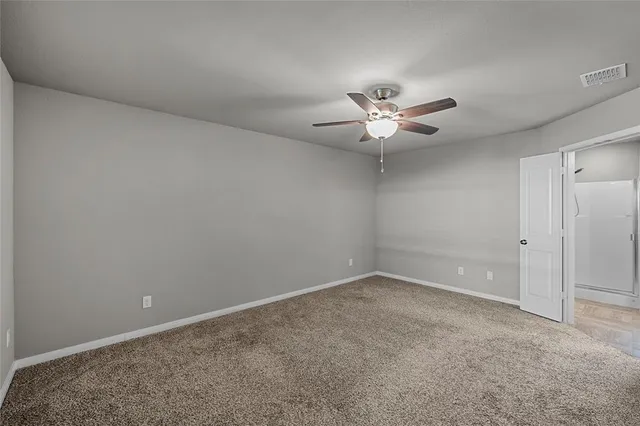 an empty room with a ceiling fan and a window