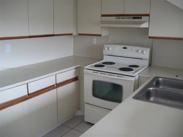 a kitchen with white cabinets and sink