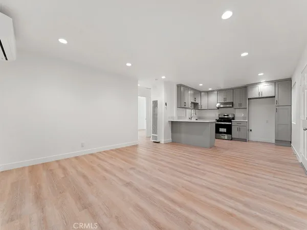 a view of kitchen with kitchen island a sink wooden floor and a refrigerator