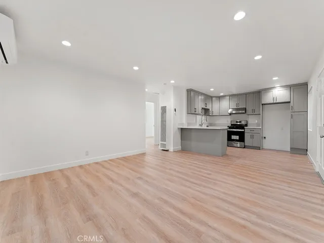 a view of kitchen with kitchen island a sink wooden floor and a refrigerator