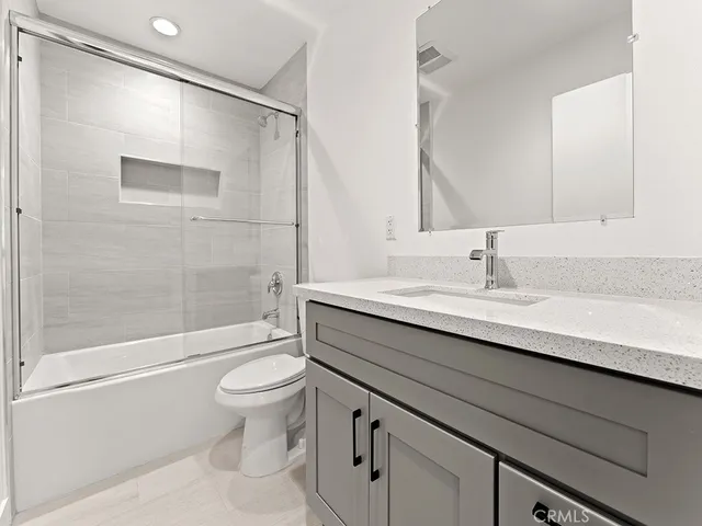 a bathroom with a sink a toilet a mirror and shower