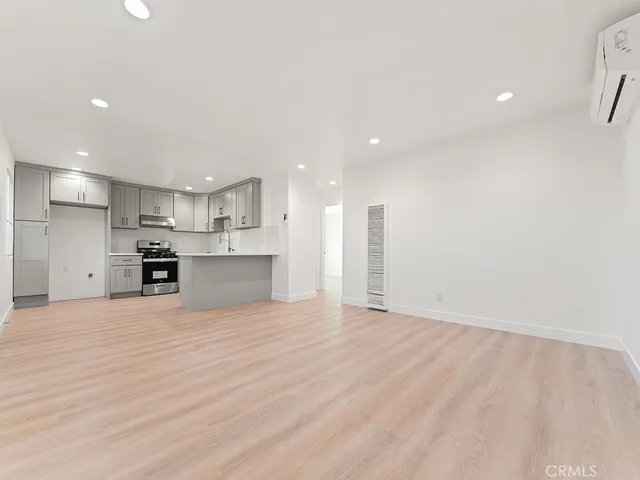 a view of kitchen with kitchen island a sink wooden floor and a refrigerator
