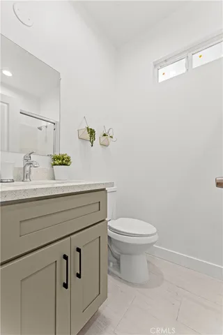 a bathroom with a granite countertop toilet sink and mirror
