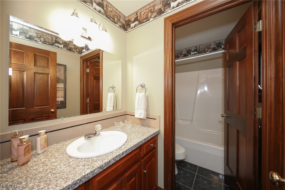 215 Georgetown-Damascus Road Beloit, OH 44609 - Photo 23 of 37 Full bathroom featuring bathing tub / shower combination, toilet, tile flooring, and oversized vanity
