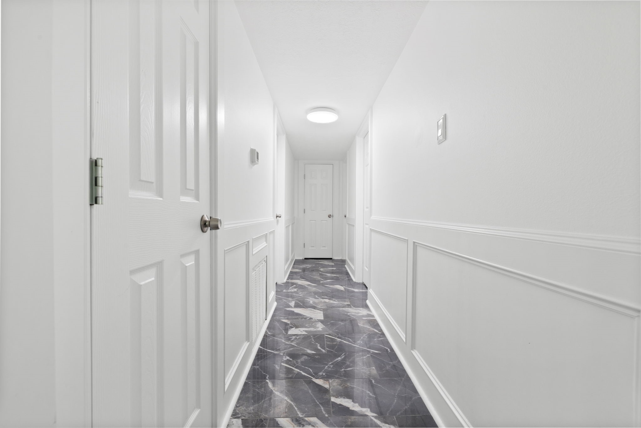 7900 Westheimer Road, Unit 121 Houston, TX 77063 - Photo 16 of 23 Bright and inviting hallway featuring elegant wainscoting and modern tile flooring leading to multiple rooms.