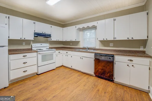 a kitchen with granite countertop white cabinets sink and stainless steel appliances