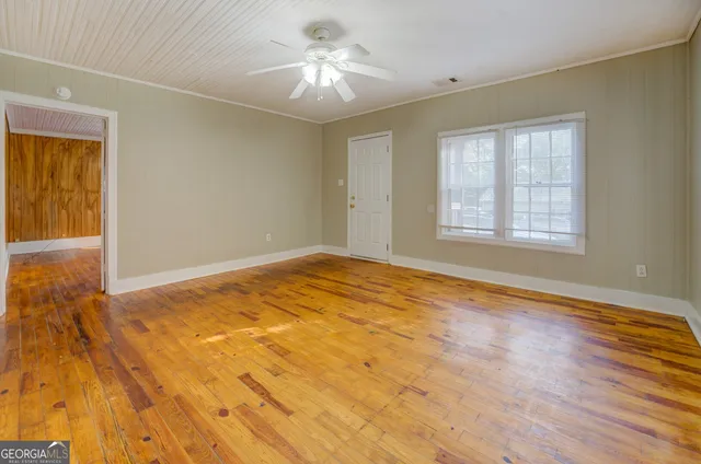 a view of empty room with wooden floor and fan