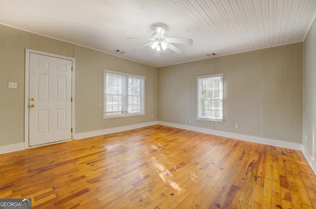 a view of an empty room with wooden floor and a window