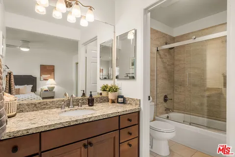 a bathroom with a granite countertop sink a toilet and shower