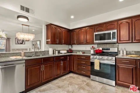 a kitchen with stainless steel appliances granite countertop wooden cabinets stove top oven and granite counter top