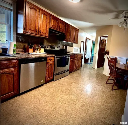 a kitchen with stainless steel appliances granite countertop a stove a sink dishwasher and a refrigerator with wooden cabinets