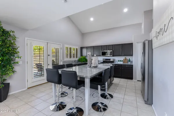 a kitchen with a dining table chairs and refrigerator