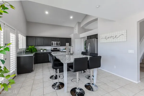 a view of kitchen with kitchen island stainless steel appliances refrigerator stove dining table and chairs