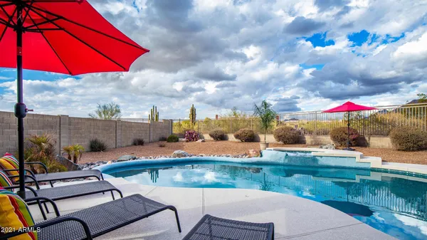 a view of swimming pool with a table and chairs under an umbrella