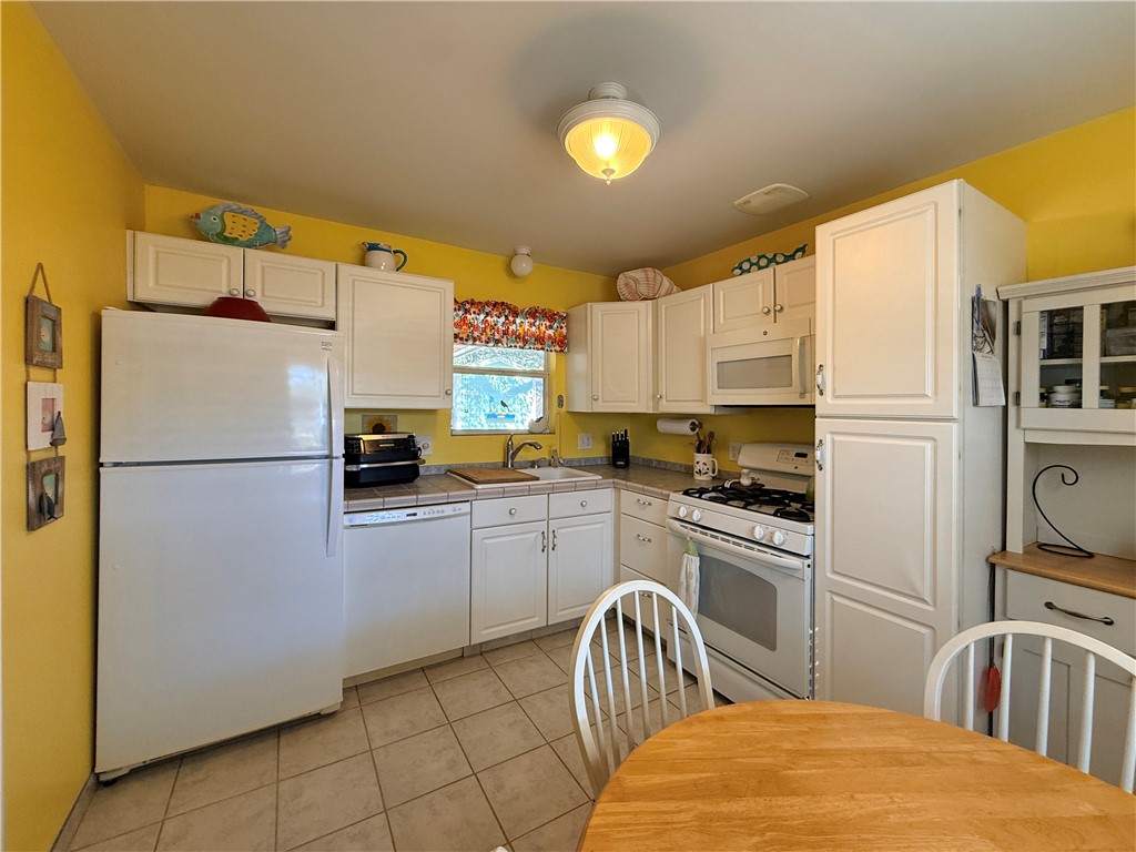 1411 Myrtle Street Fulton, TX 78358 - Photo 10 of 26 a kitchen with a refrigerator a stove a sink dishwasher and cabinets