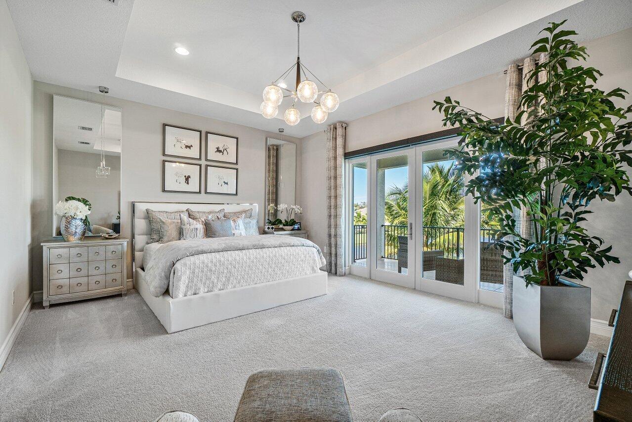 11655 Windy Frst Way Boca Raton, FL 33498 - Photo 25 of 50 a spacious bedroom with a balcony a bed and a chandelier