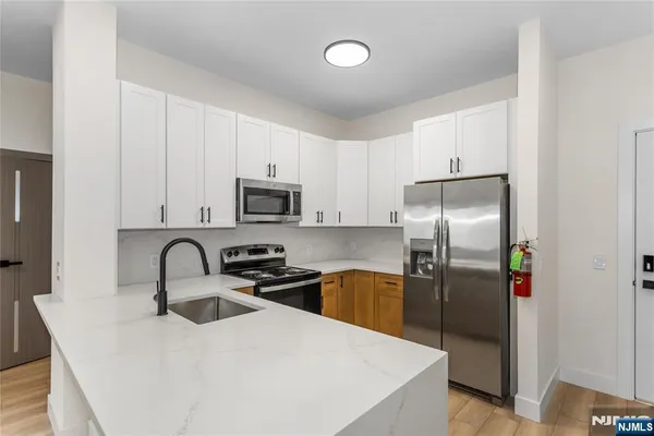 a kitchen with stainless steel appliances a refrigerator a sink a stove and cabinets