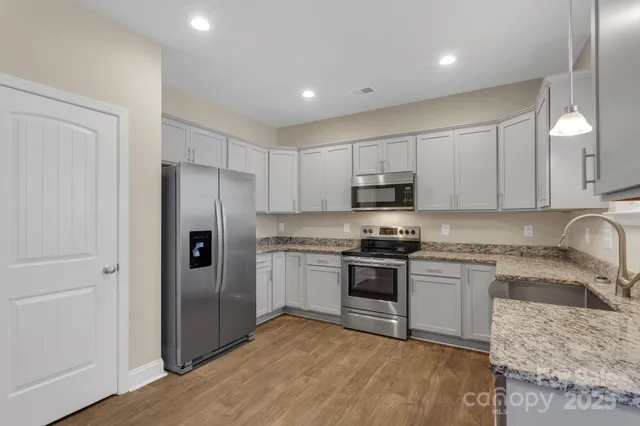 a kitchen with stainless steel appliances granite countertop a refrigerator stove top oven and sink