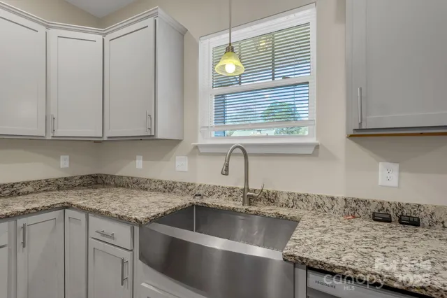 a kitchen with granite countertop a sink a window and cabinets