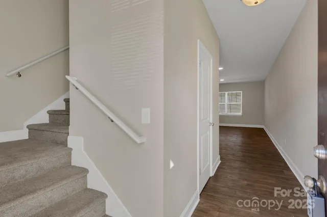 a view of a hallway with wooden floor and staircase