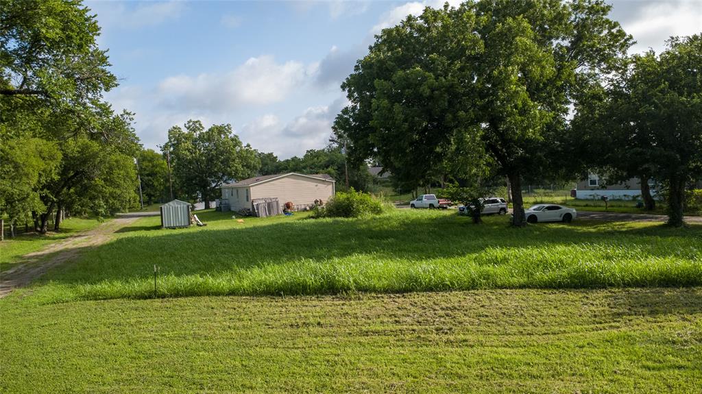 103 Atlantic Street Cleburne, TX 76031 - Photo 4 of 5 Expansive grassy lot featuring mature trees and a detached storage shed