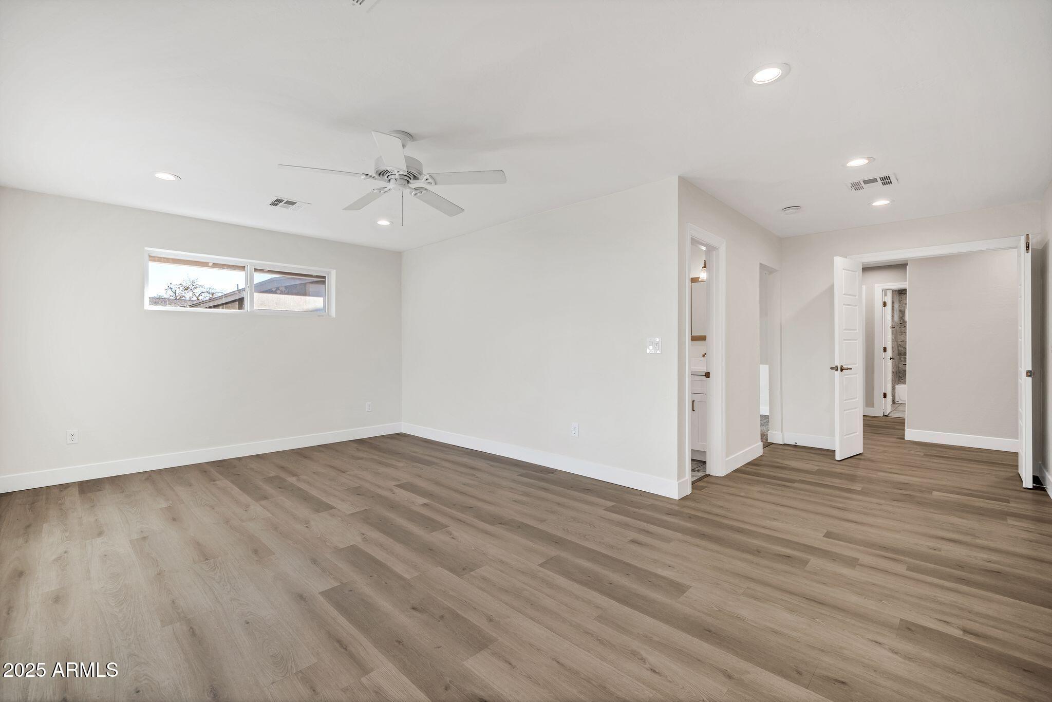 641 West Linger Lane Phoenix, AZ 85021 - Photo 14 of 38 an empty room with wooden floor ceiling fan and windows