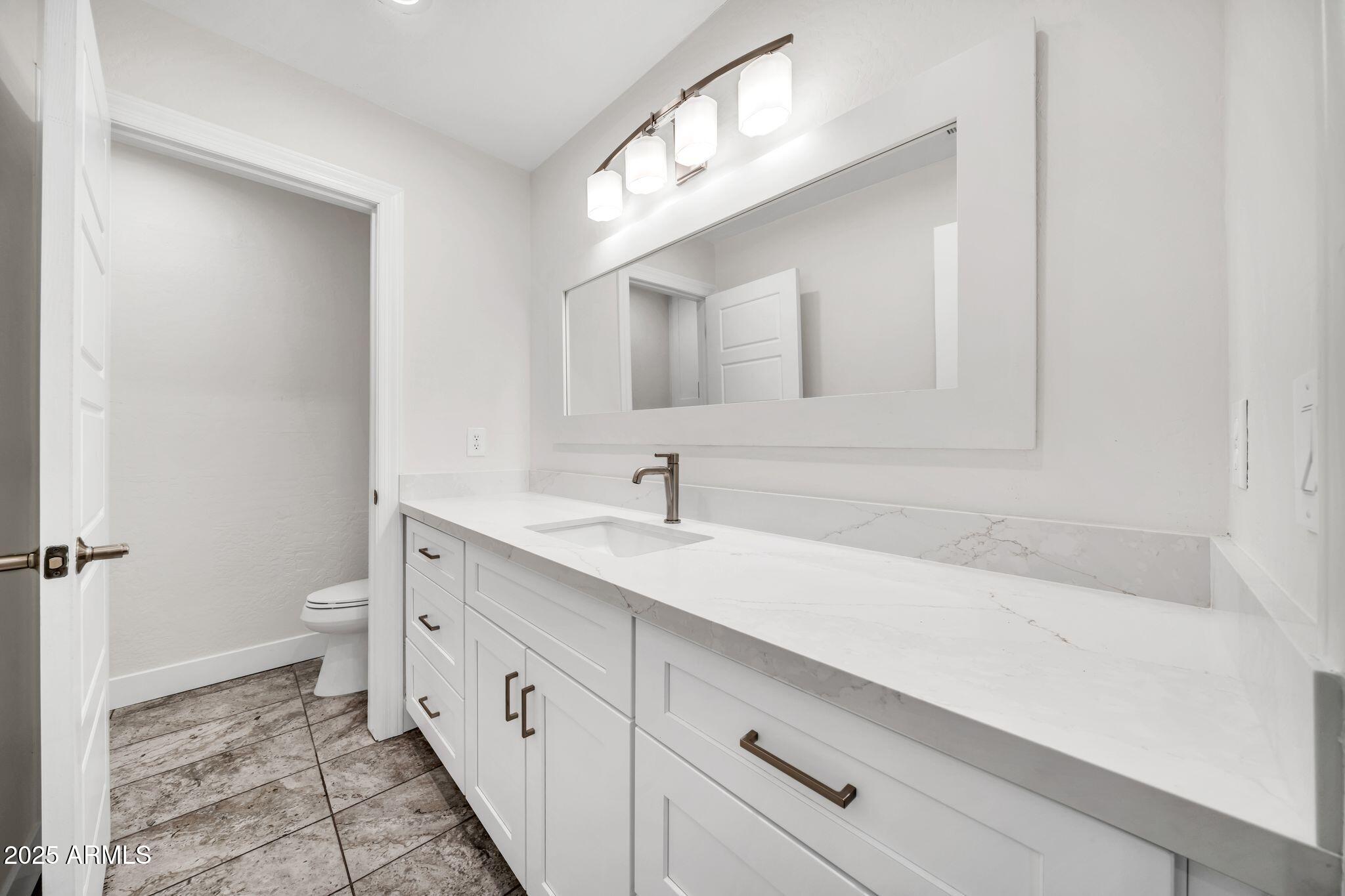 641 West Linger Lane Phoenix, AZ 85021 - Photo 28 of 38 a spacious bathroom with a double vanity sink a toilet and a mirror