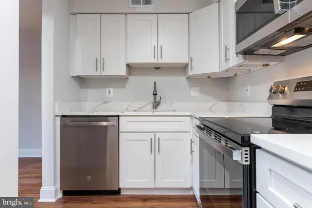 a kitchen with granite countertop a sink stainless steel appliances and cabinets