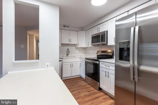 a kitchen with cabinets stainless steel appliances and a window