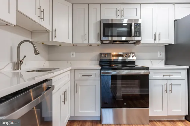 a kitchen with granite countertop white cabinets and stainless steel appliances