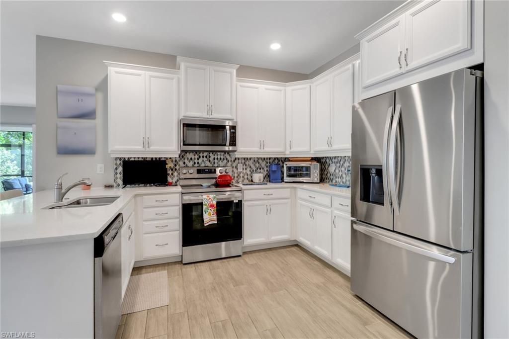 1256 Enbrook Loop Naples, FL 34114 - Photo 4 of 35 a kitchen with stainless steel appliances a refrigerator stove microwave and sink