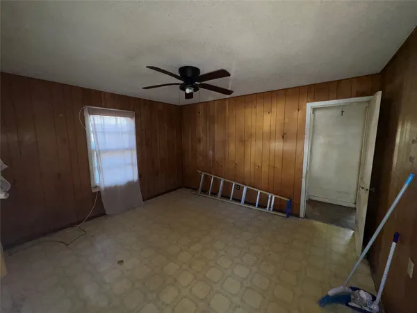 an empty room with windows and fan