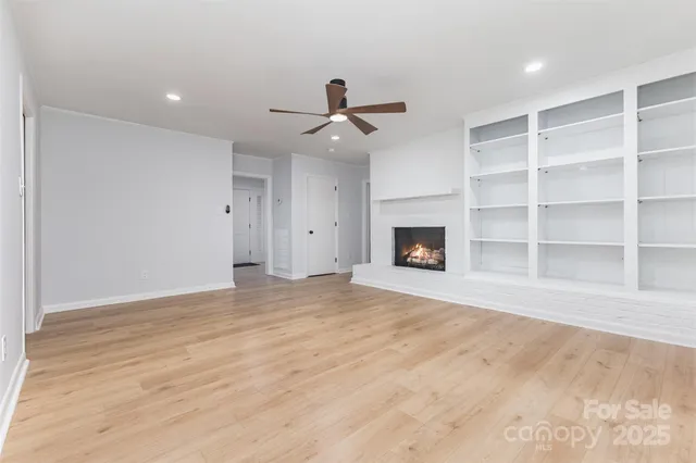 a view of empty room with wooden floor and ceiling fan
