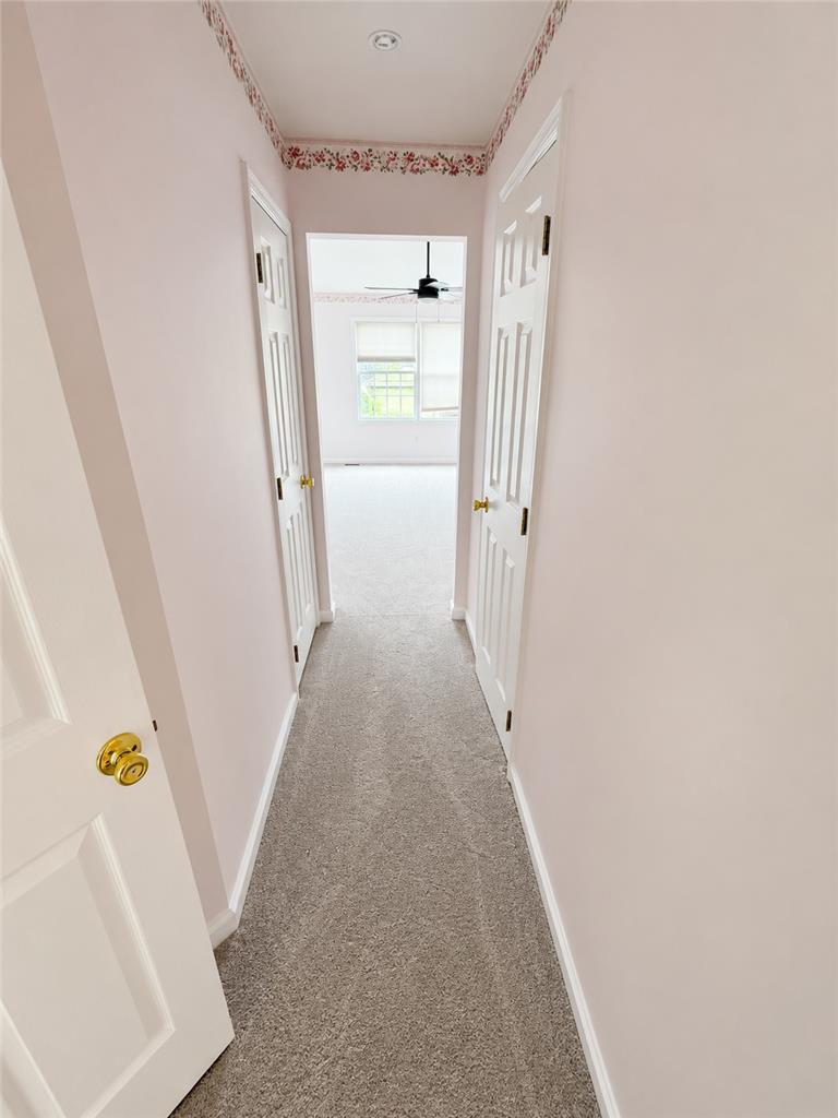 511 Howertown Road Northampton, PA 18067 - Photo 15 of 34 A well-maintained carpeted hallway leads to a room beyond, featuring a ceiling fan and sun-filled windows.