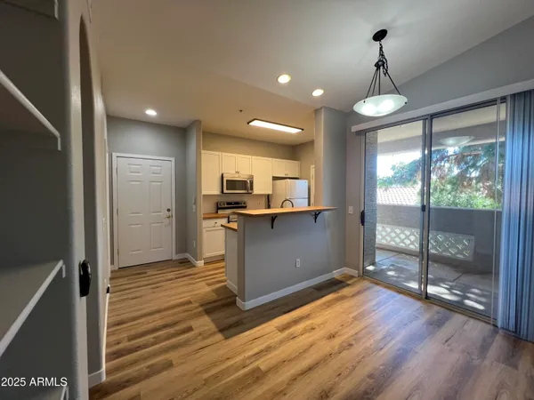 a open kitchen with a refrigerator and wooden floor